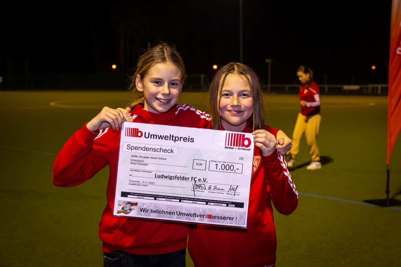 Zwei Mädchen mit Spendencheck in der Hand.